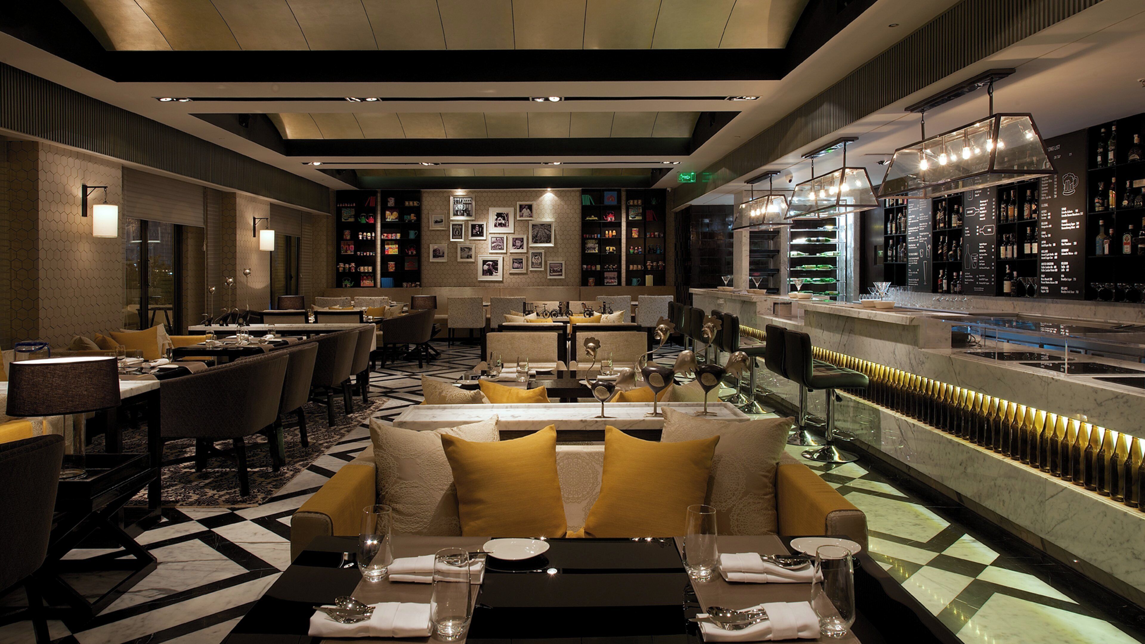 A restaurant with a bar area, seating arrangements, and a checkered floor pattern.