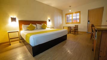 Ein Hotelzimmer mit einem großen Bett, einem Schreibtisch, einem Sessel und einem Fenster mit Jalousien.