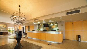 A hotel lobby with a reception desk, a large chandelier, and a modern design. - Hotel Colonial Mexicali (Mexicali)