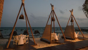 A beach setting with wooden structures, tables, and chairs. - El Dorado Royale, All & More Inclusive Adults Only (Playa del Carmen)