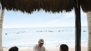 A beachside dining setup with a thatched roof, a white table with plates of food, and a view of the ocean. - El Dorado Royale, All & More Inclusive Adults Only (Playa del Carmen)