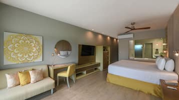A modern hotel room with a bed, a desk, a sofa, a TV, and a ceiling fan.