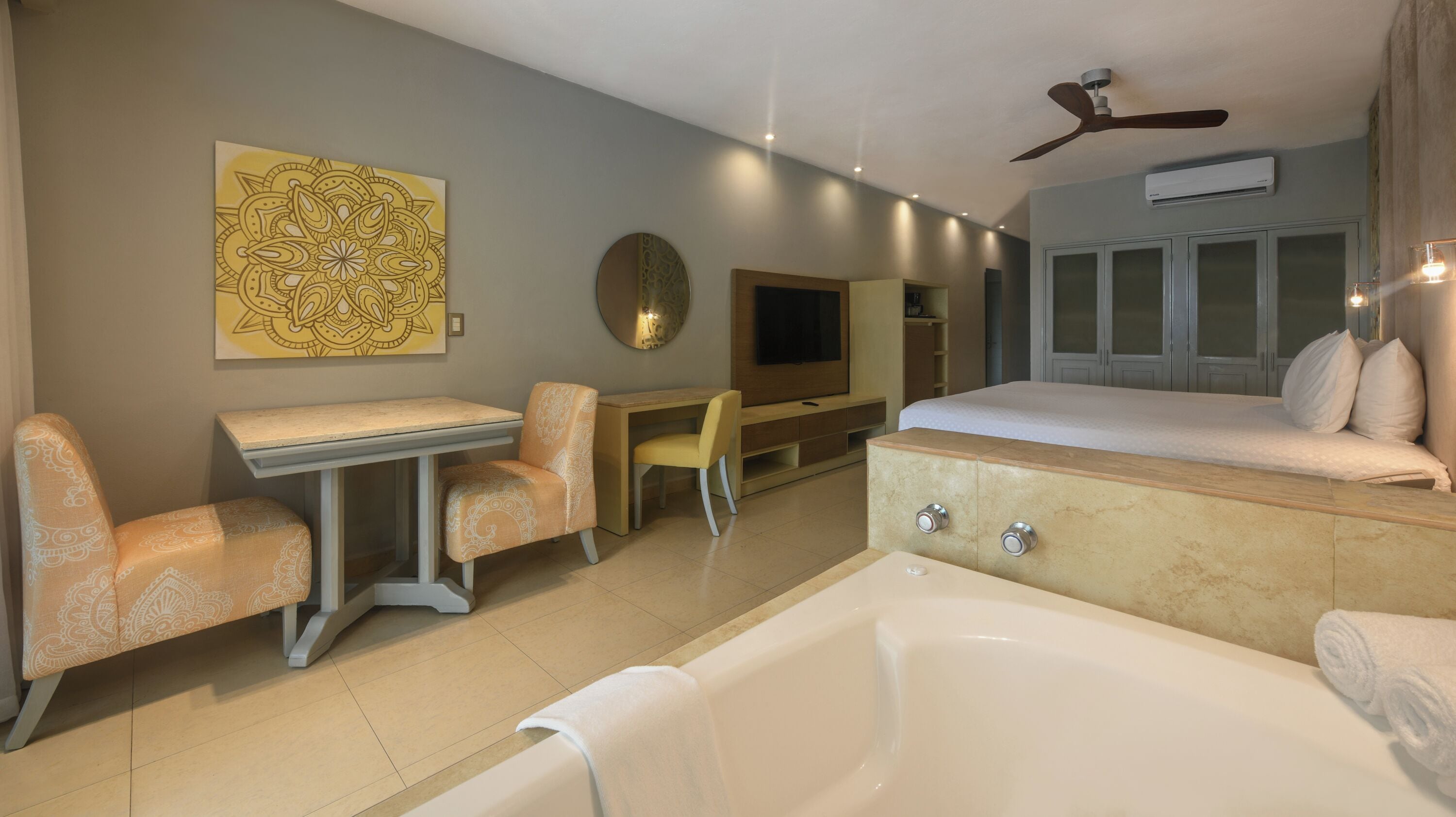Una habitación de hotel moderna con una cama grande, un escritorio independiente con una silla, una bañera y un televisor.