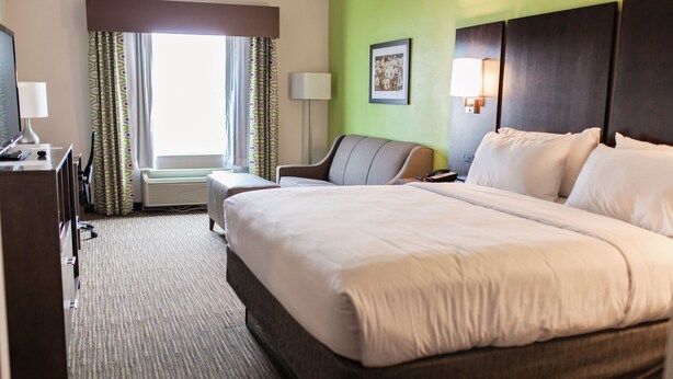 A hotel room with a large bed, a desk with a lamp, a chair, and a window with curtains. - Holiday Inn Express & Suites Sweetwater by IHG (Sweetwater)
