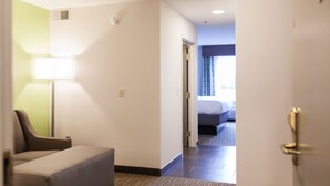 A hotel room with a bed, a desk, and a chair. There is a door leading to another room. - Holiday Inn Express & Suites Sweetwater by IHG (Sweetwater)