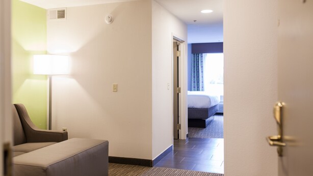 A hotel room with a bed, a desk, and a chair. There is a door leading to another room. - Holiday Inn Express & Suites Sweetwater by IHG (Sweetwater)
