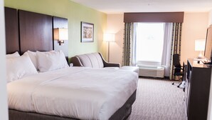 A hotel room with a large bed, a desk, a chair, a desk lamp, a picture on the wall, and an air conditioning unit. - Holiday Inn Express & Suites Sweetwater by IHG (Sweetwater)