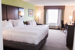 Une chambre d’hôtel avec un grand lit, un bureau, une chaise, une lampe de bureau, un tableau au mur et un appareil de climatisation.