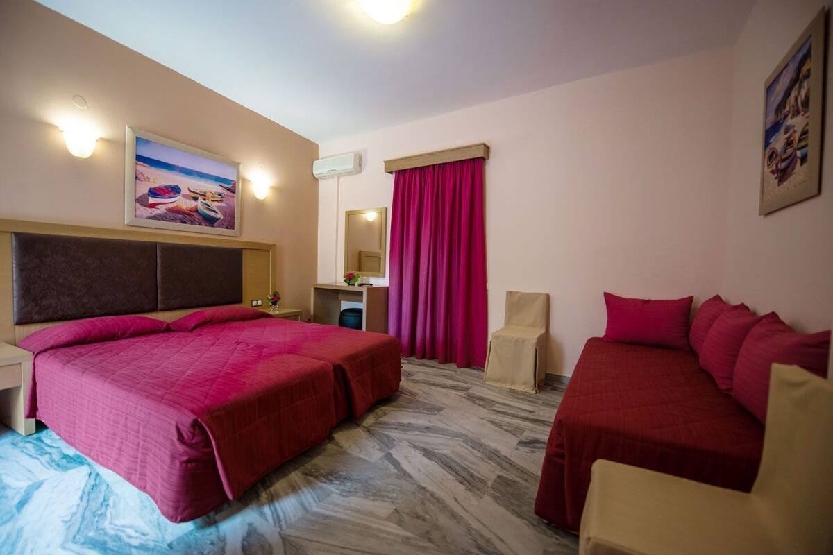 A hotel room with a large bed, a smaller bed, a desk with a chair, a mirror, and a painting on the wall.