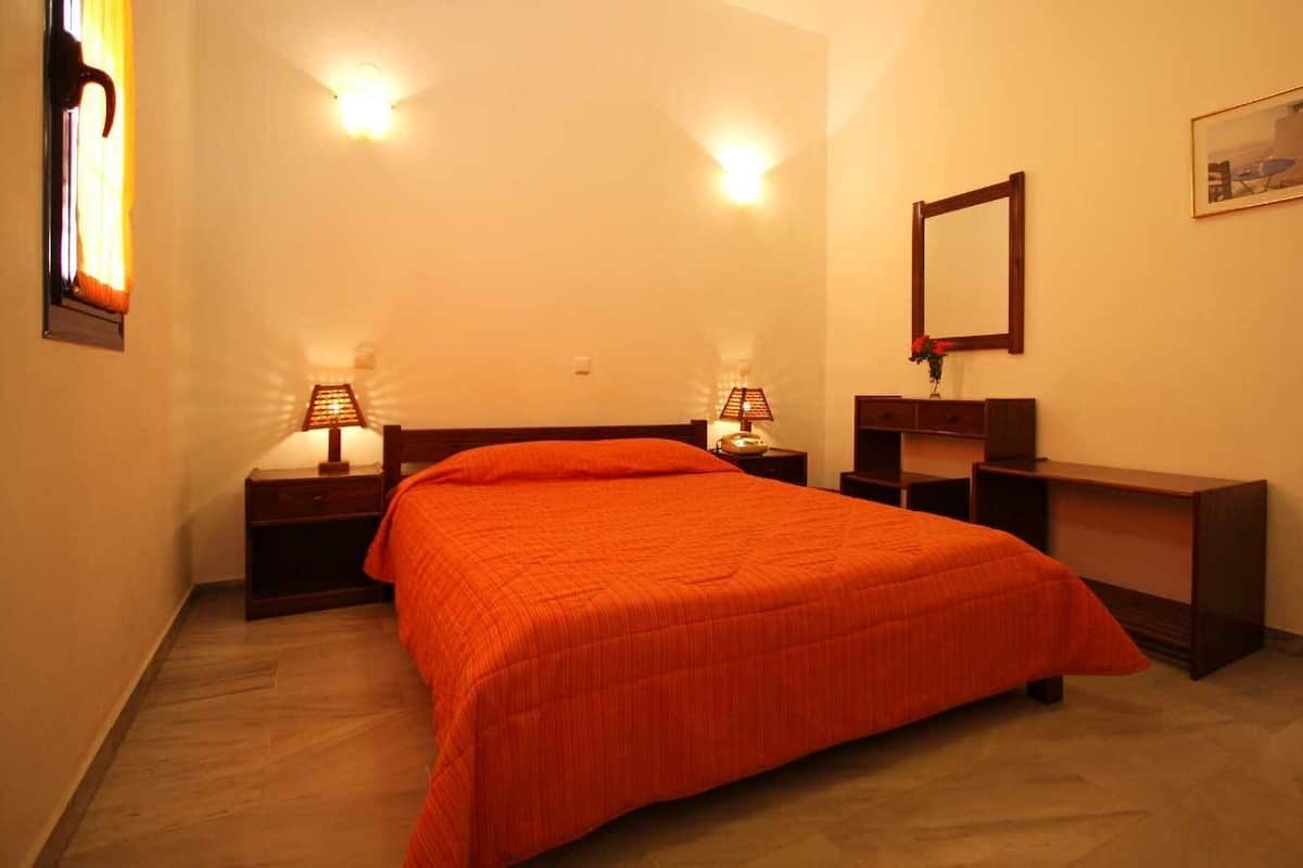 A bedroom with a bed, two bedside tables with lamps, a nightstand, a dresser, a mirror, and a framed picture on the wall.