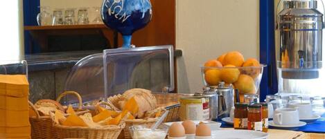 Disposição de buffet de café da manhã com pães, ovos e laranjas.