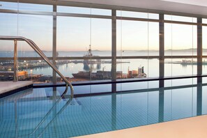 Una piscina techada, una piscina al aire libre, sombrillas