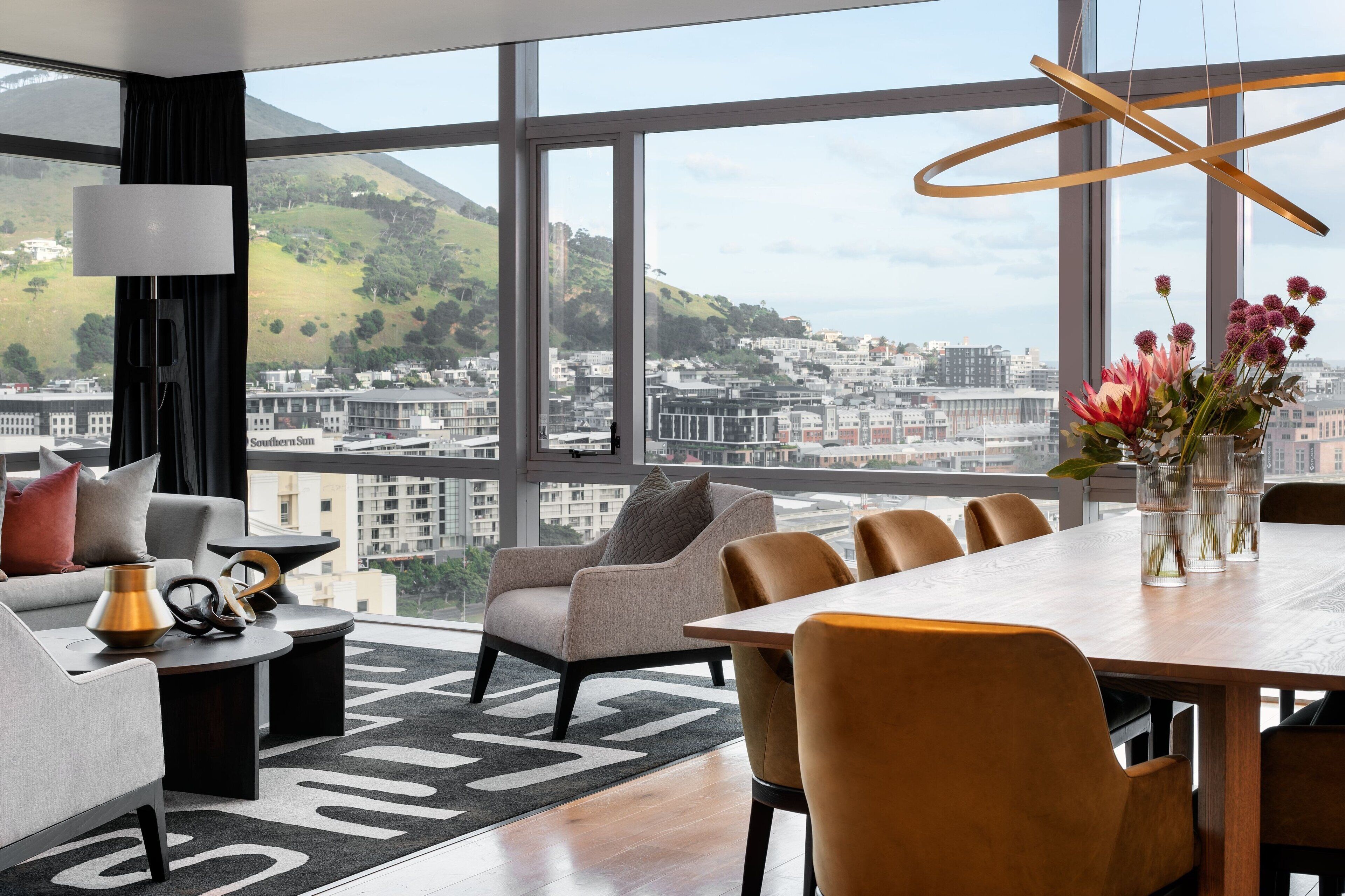 A modern living room with a large window, a dining table, and comfortable seating.