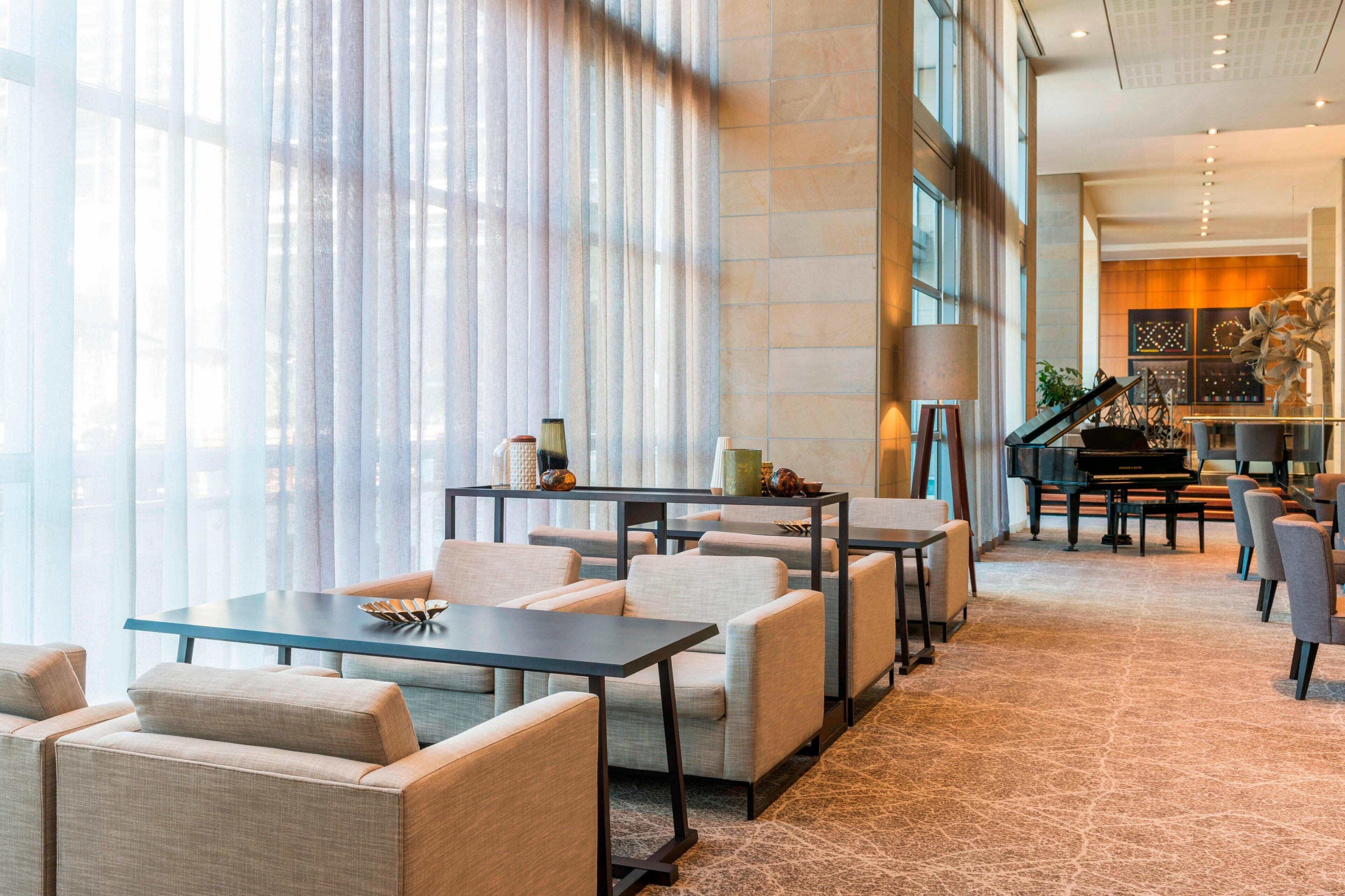 A spacious lobby with a piano, seating area, and large windows.