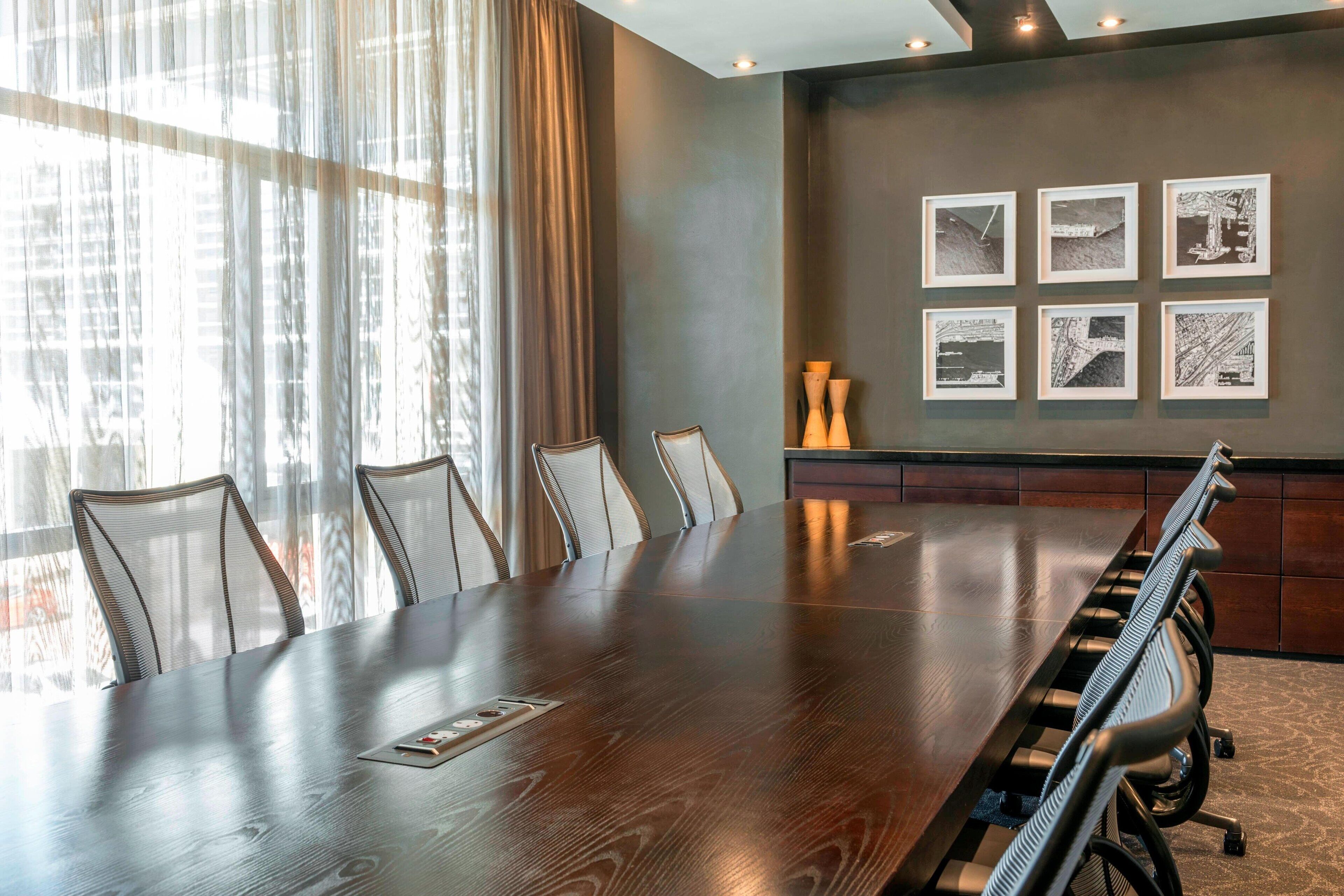 A conference room with a long table, six chairs, and six framed black and white photographs on the wall.