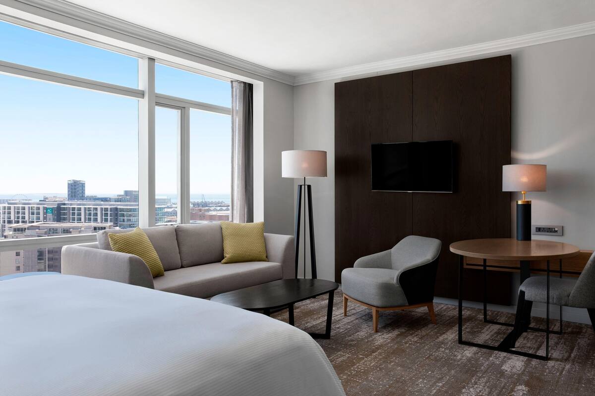 Een hotelkamer met een groot bed, een bank, twee fauteuils, een kleine tafel en een aan de muur bevestigde televisie.