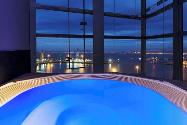 Una piscina techada, una piscina al aire libre, sombrillas