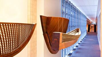 A corridor with modern wooden art installations and a view of a building through large windows.