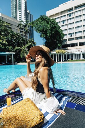 A person sitting by a pool with a cityscape in the background.