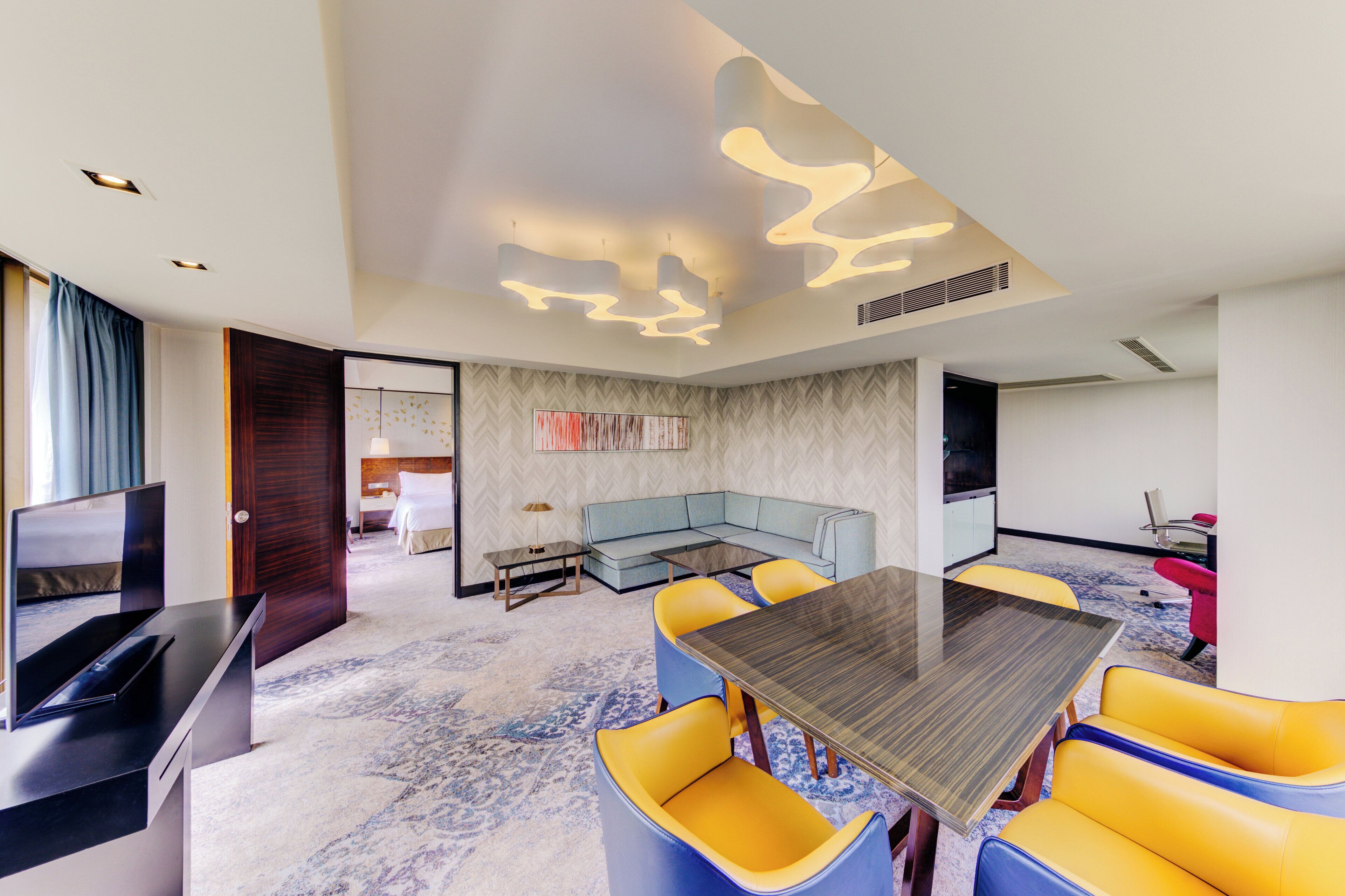 Una habitación de hotel moderna con comedor, sofá y televisor.
