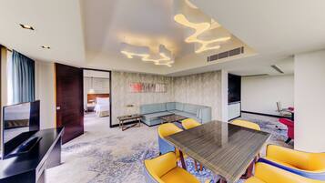 Una habitación de hotel moderna con comedor, sofá y televisor.