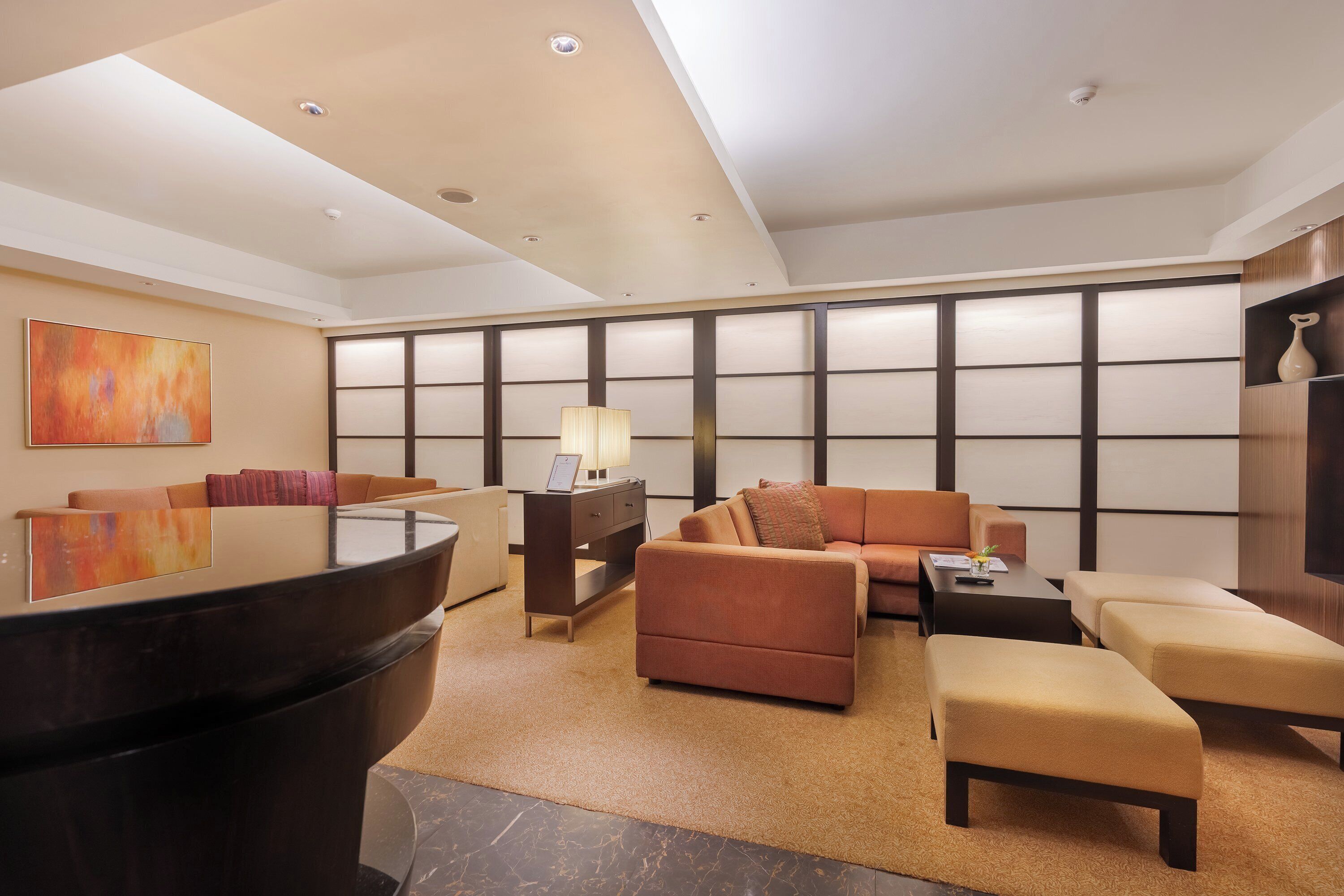 A modern living room with a sofa, ottoman, and a large black table.