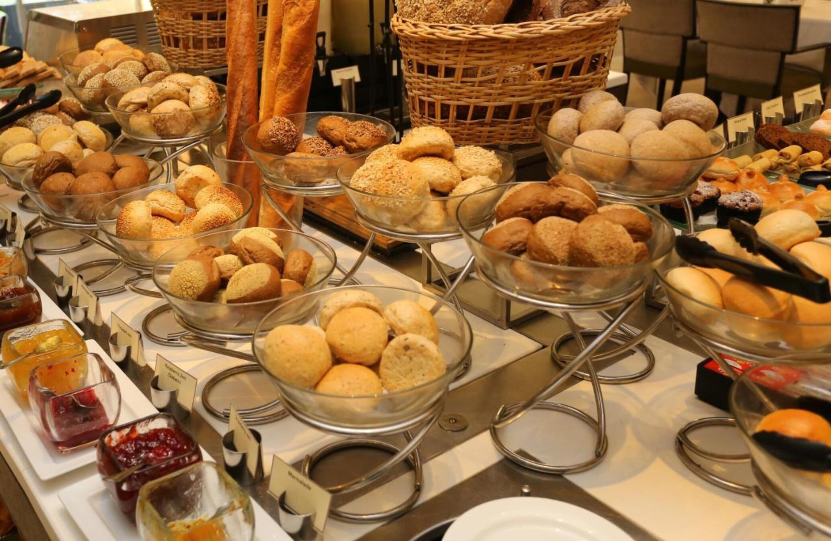 Un buffet con diversi prodotti da forno e dolci esposti in ciotole trasparenti.