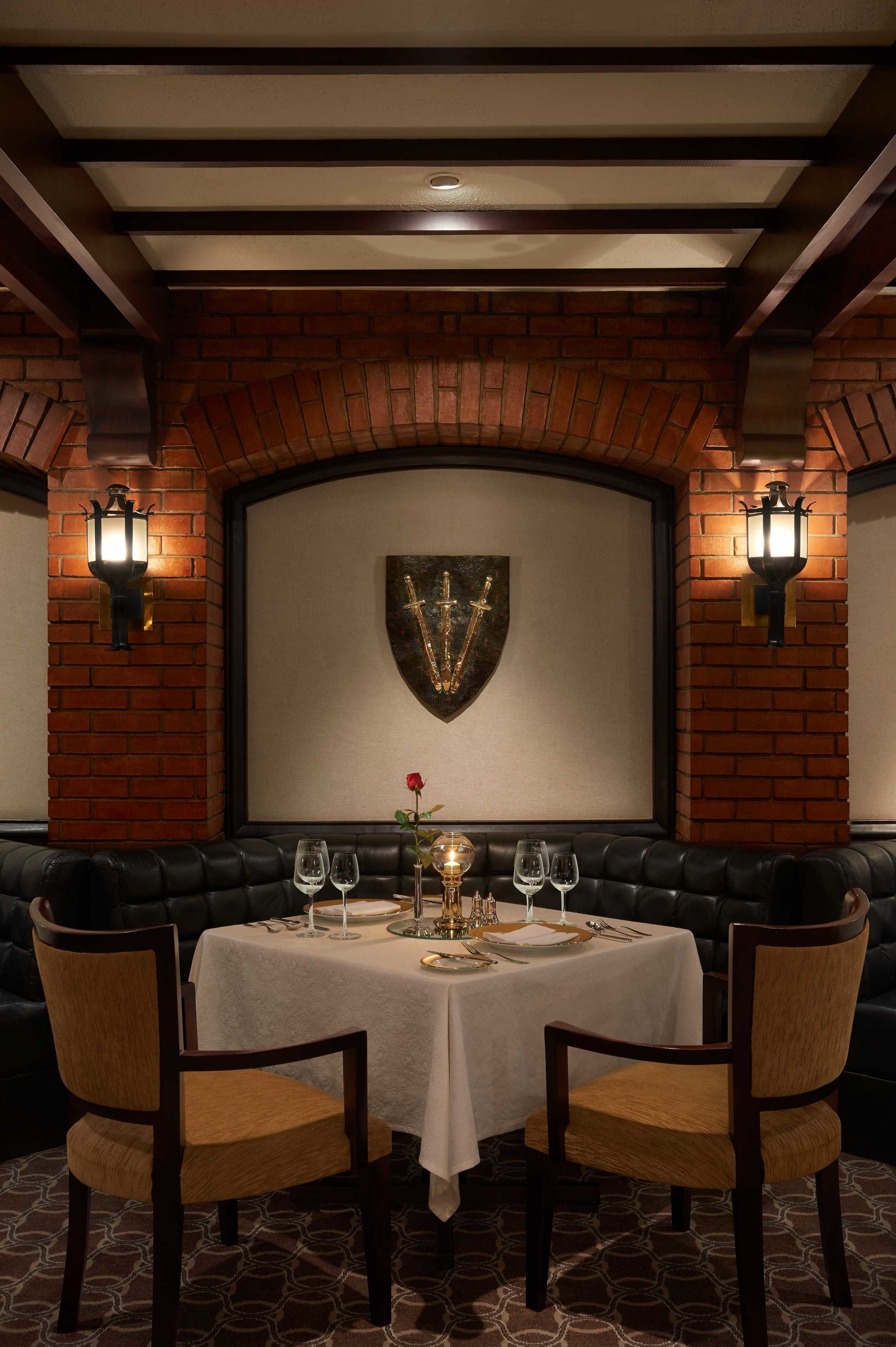 A dining area with a brick wall, a shield-shaped decoration, and a table set for four.