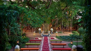 A garden wedding setup with a central aisle, benches, and decorative lighting.