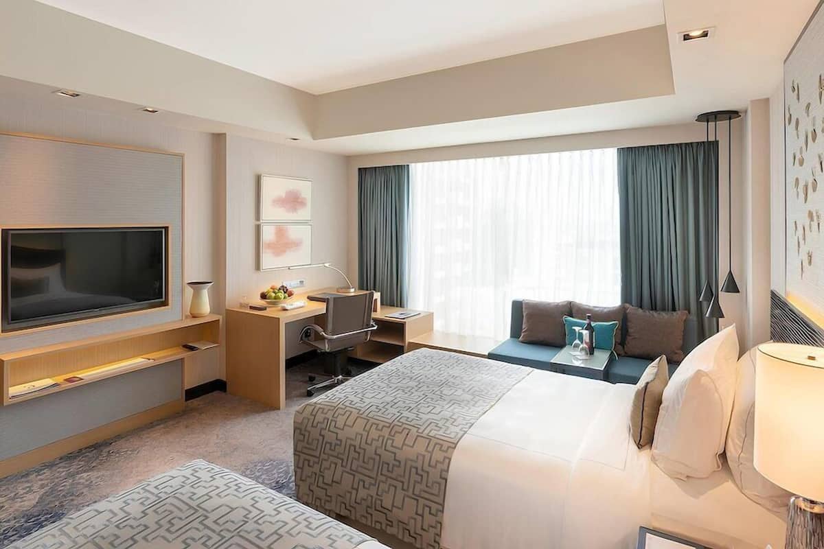 Ett hotellrum med en säng, ett skrivbord, en tv, en stol och en soffa.