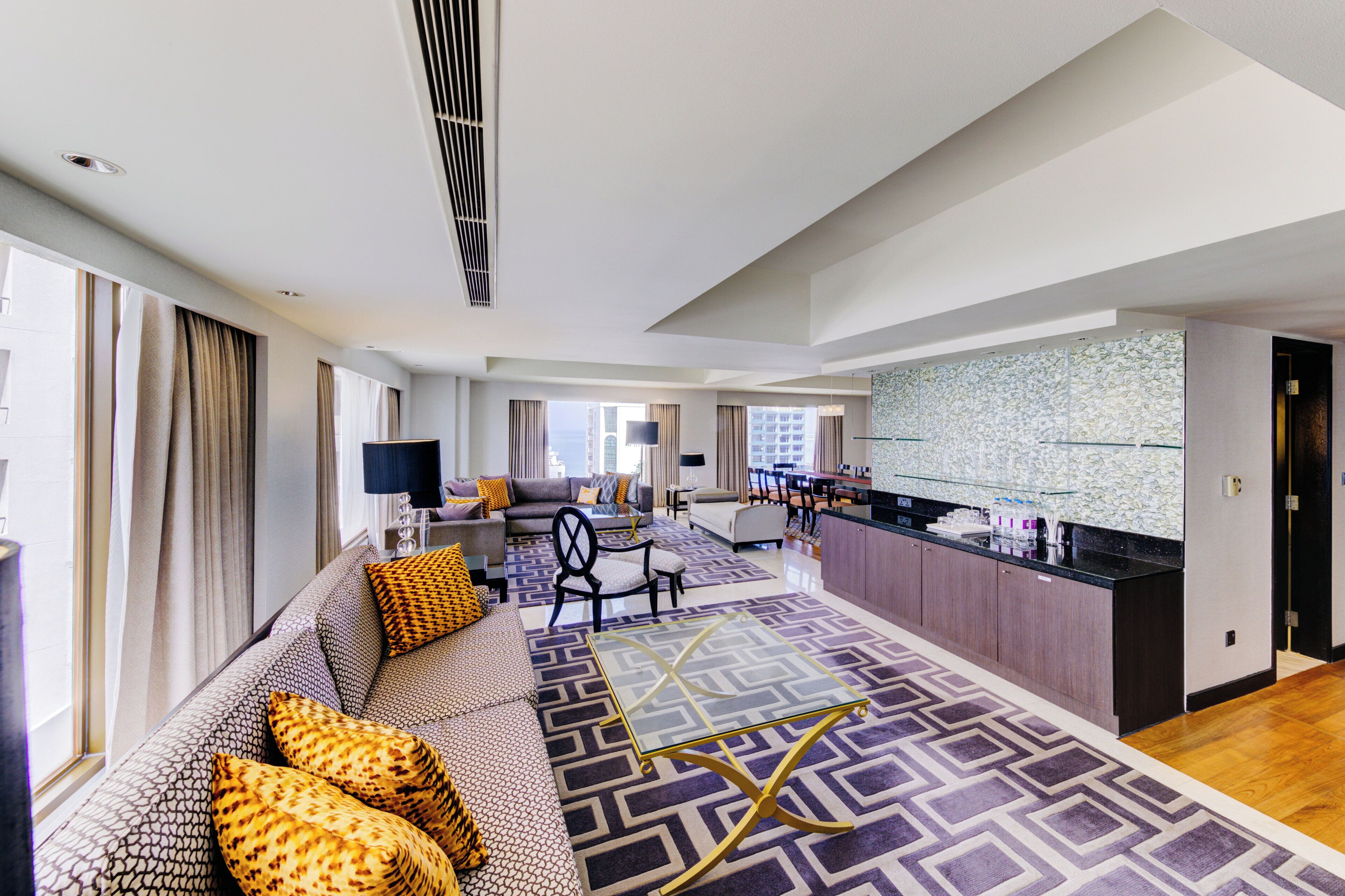Een moderne hotelkamer met een bank, een eethoek en een keuken.