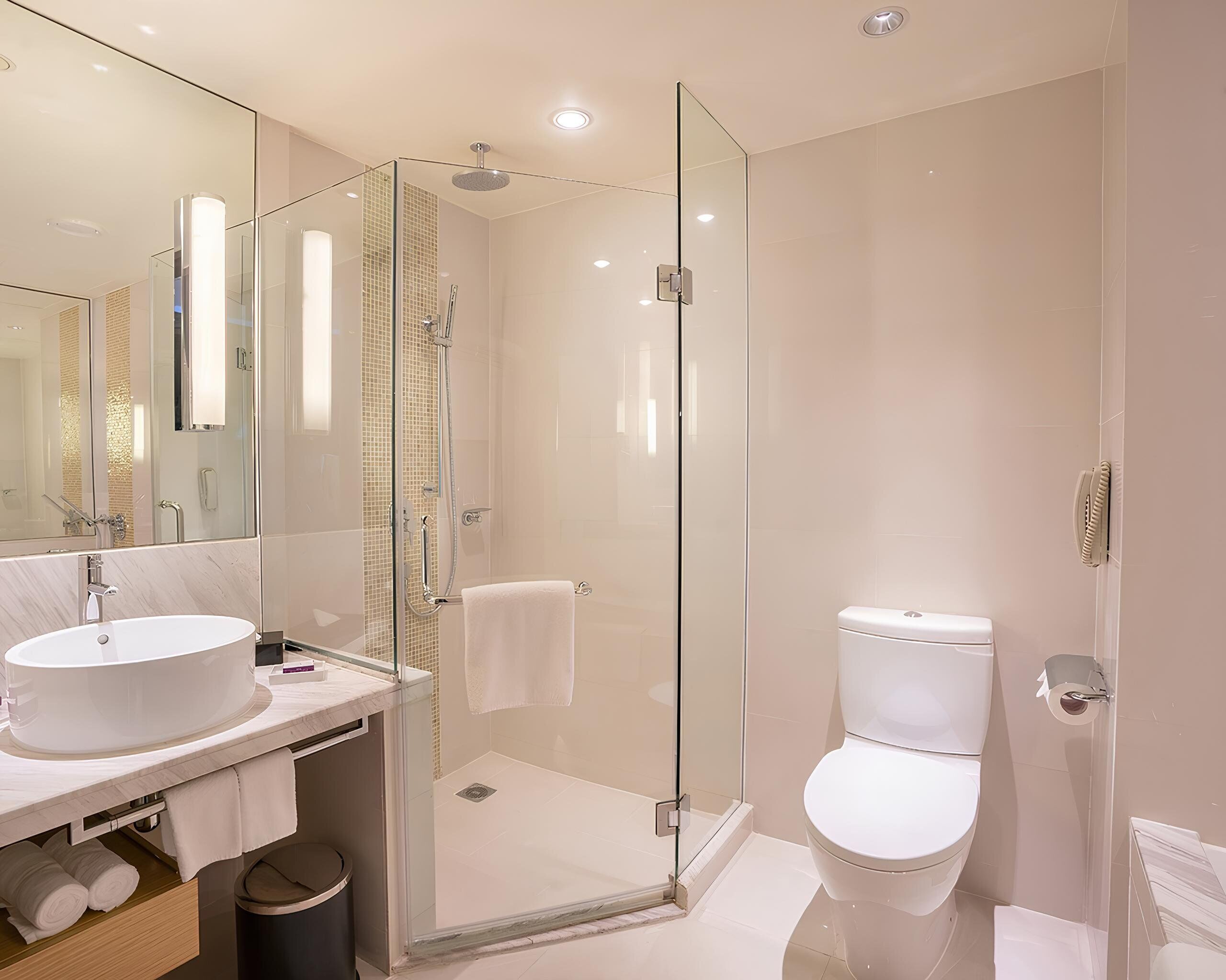 A modern bathroom with a glass-enclosed shower, a white sink, and a toilet.