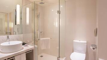 A modern bathroom with a glass-enclosed shower, a white sink, and a toilet.