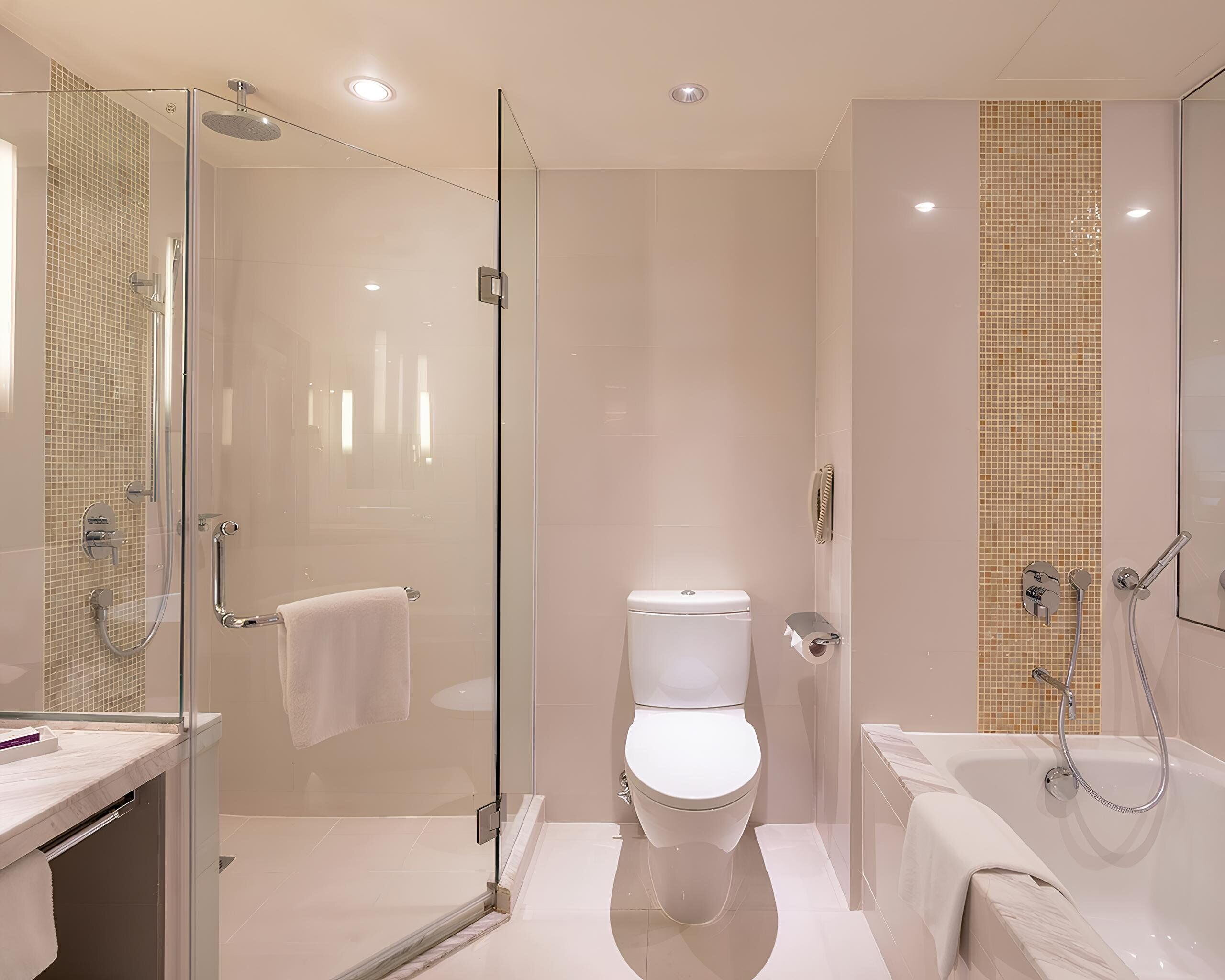 Ein modernes Badezimmer mit einer begehbaren Glasdusche, einer Toilette und einer Badewanne.