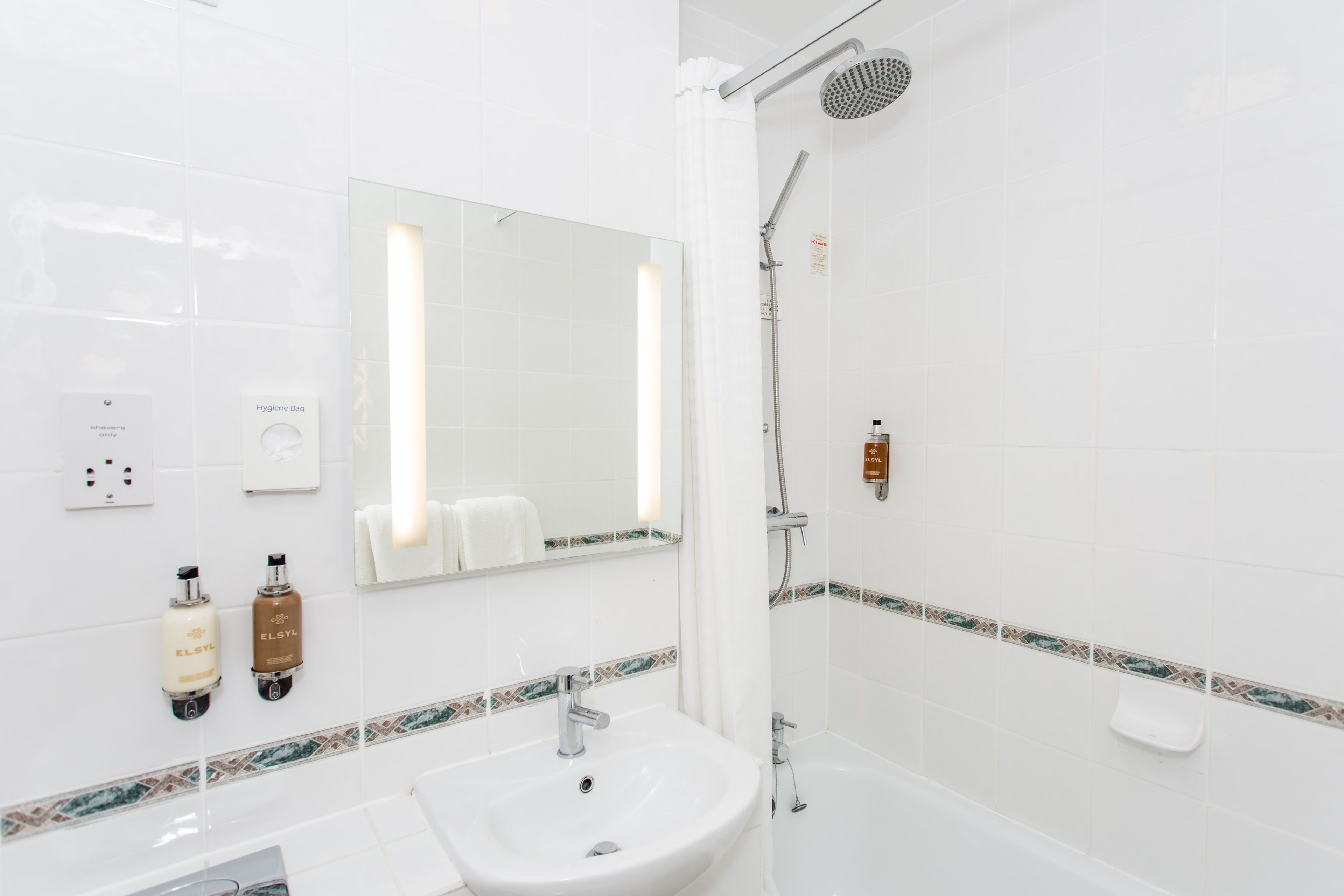 A modern bathroom with a white sink, a mirror, a shower, and a toilet.