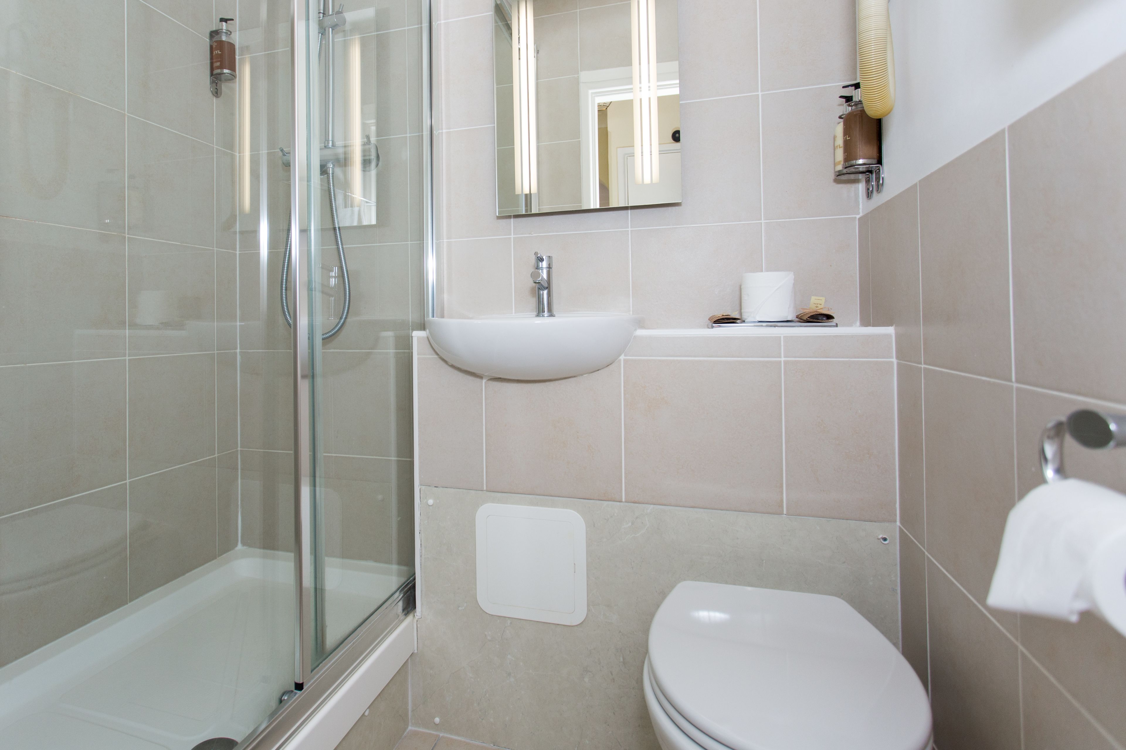 Een moderne badkamer met een douchecabine van glas, een witte wastafel en een toilet.
