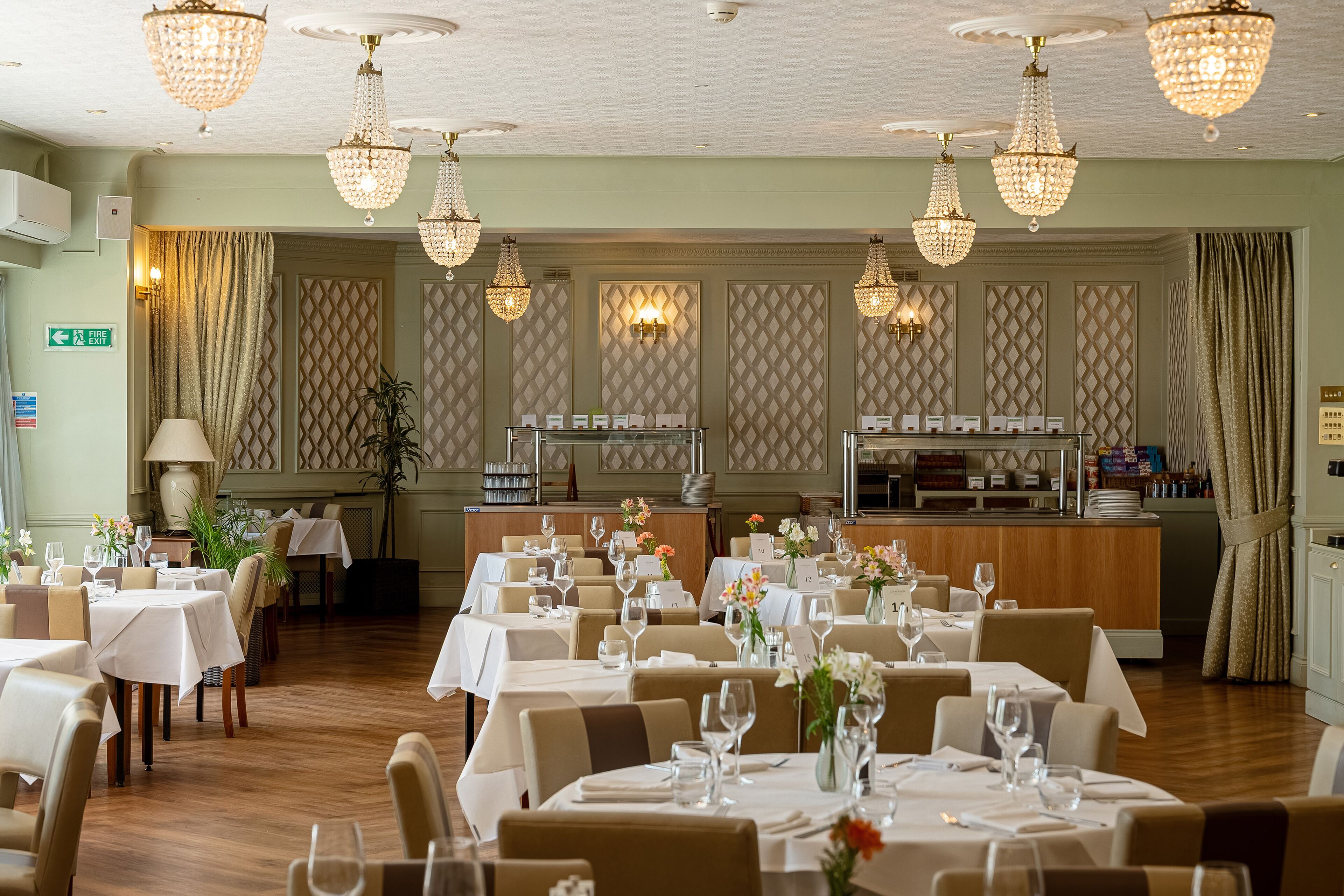 Un restaurant doté de nombreuses tables, de lustres et d’un bar.