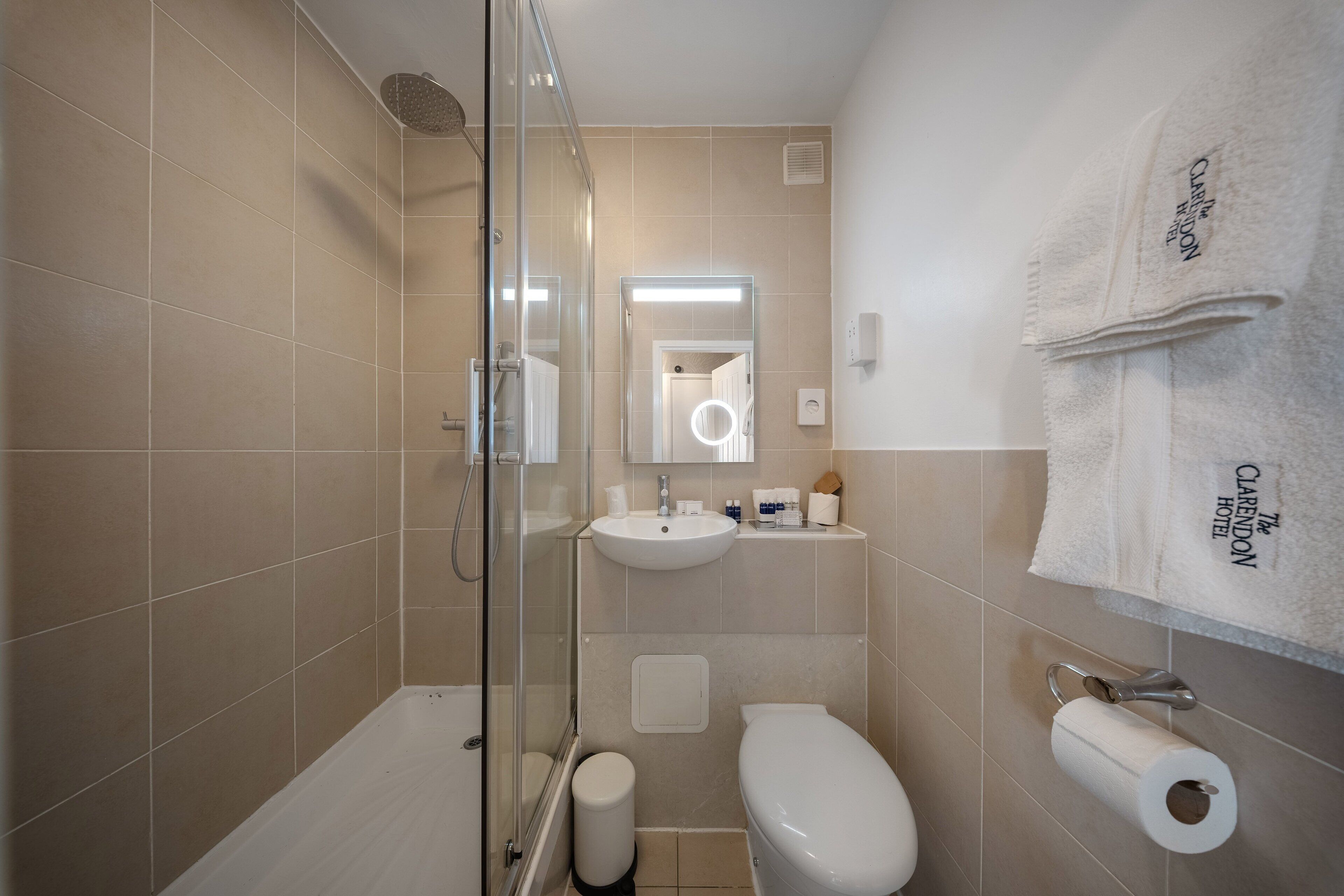 Un baño moderno con cabina de ducha de vidrio, un lavamanos blanco y un inodoro.