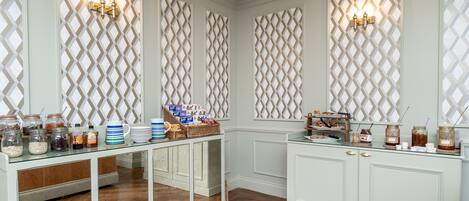 Uma cozinha com armários brancos, uma mesa de vidro com alimentos e painéis decorativos na parede.