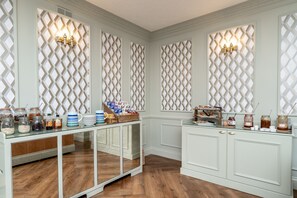 Une cuisine avec des meubles blancs, une table à plateau en verre sur laquelle sont disposés des aliments, et des panneaux décoratifs sur les murs.