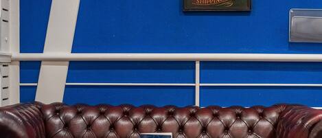 Una habitación con pared azul, sofá de cuero marrón y mesa de madera.
