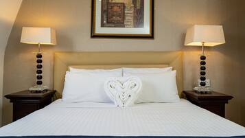A hotel room with a neatly made bed, two bedside lamps, and a framed artwork on the wall.