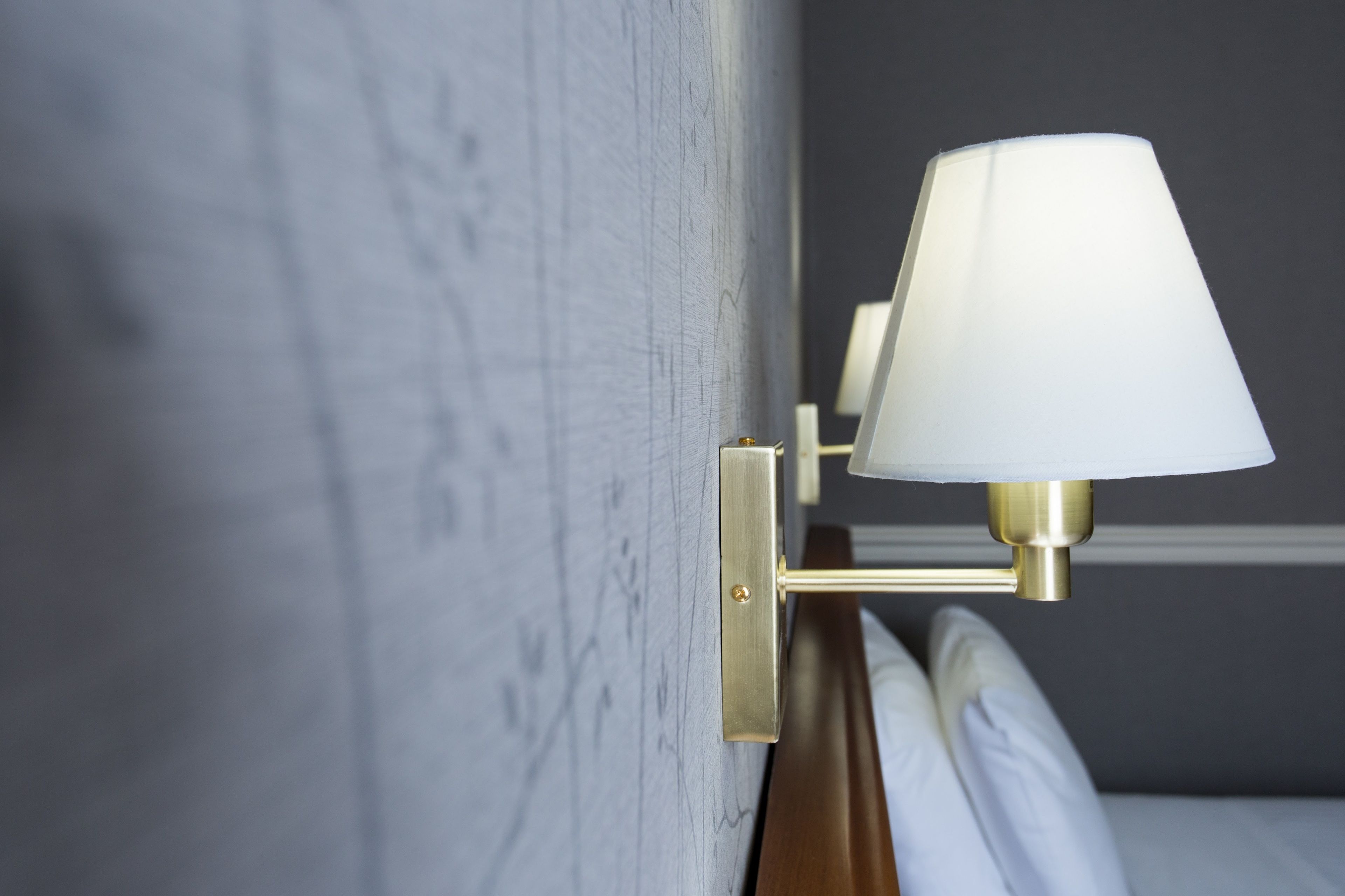 A wall-mounted lamp with a white shade and brass fixtures.