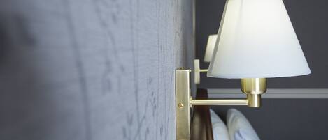 A wall-mounted lamp with a white shade and brass fixtures.