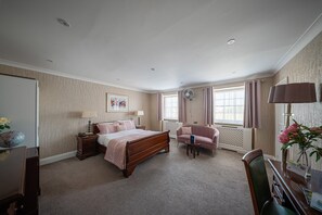Une chambre à coucher comprenant un lit, des tables de chevet, une chaise, un bureau et une lampe.