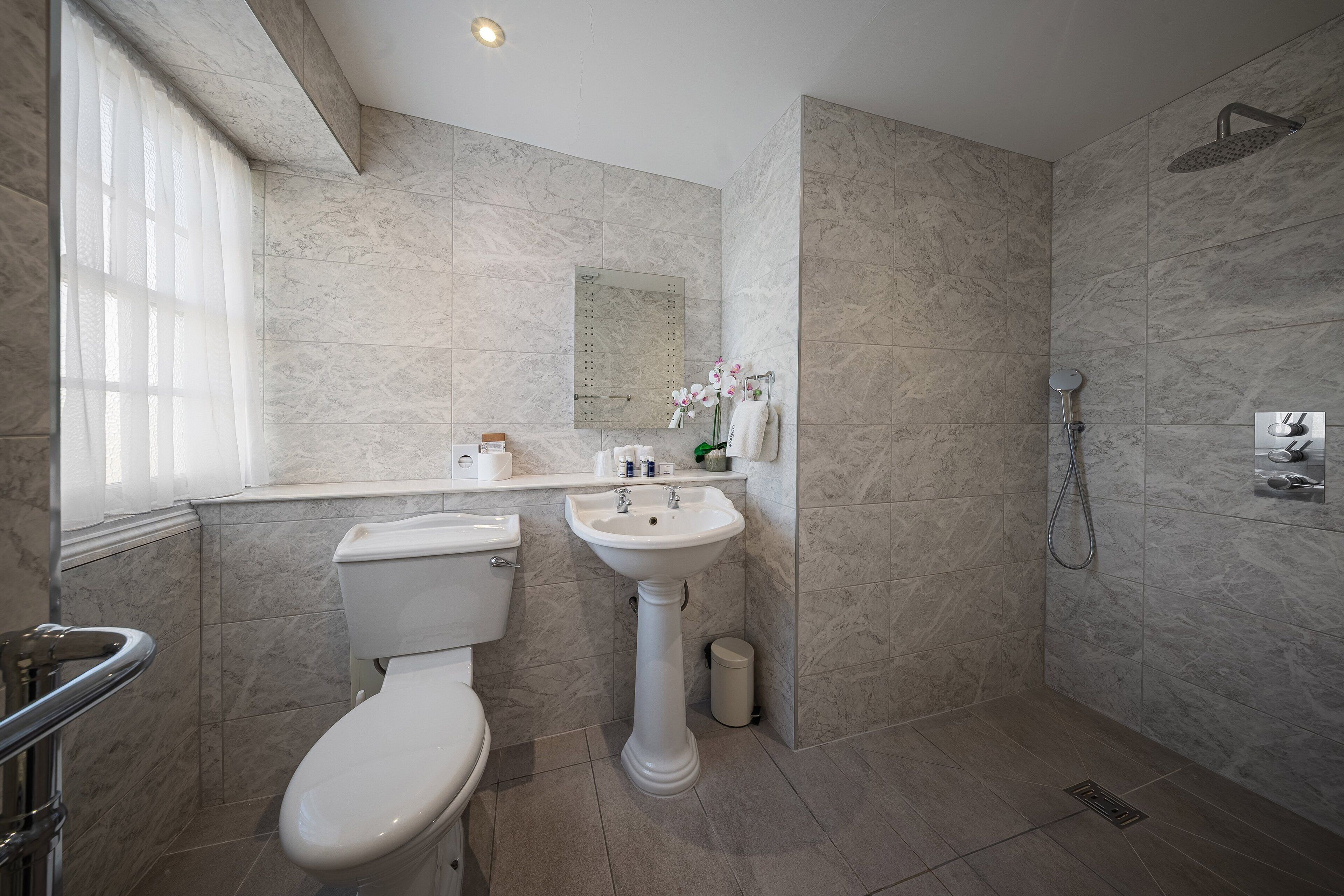 A bathroom with a toilet, sink, and shower.