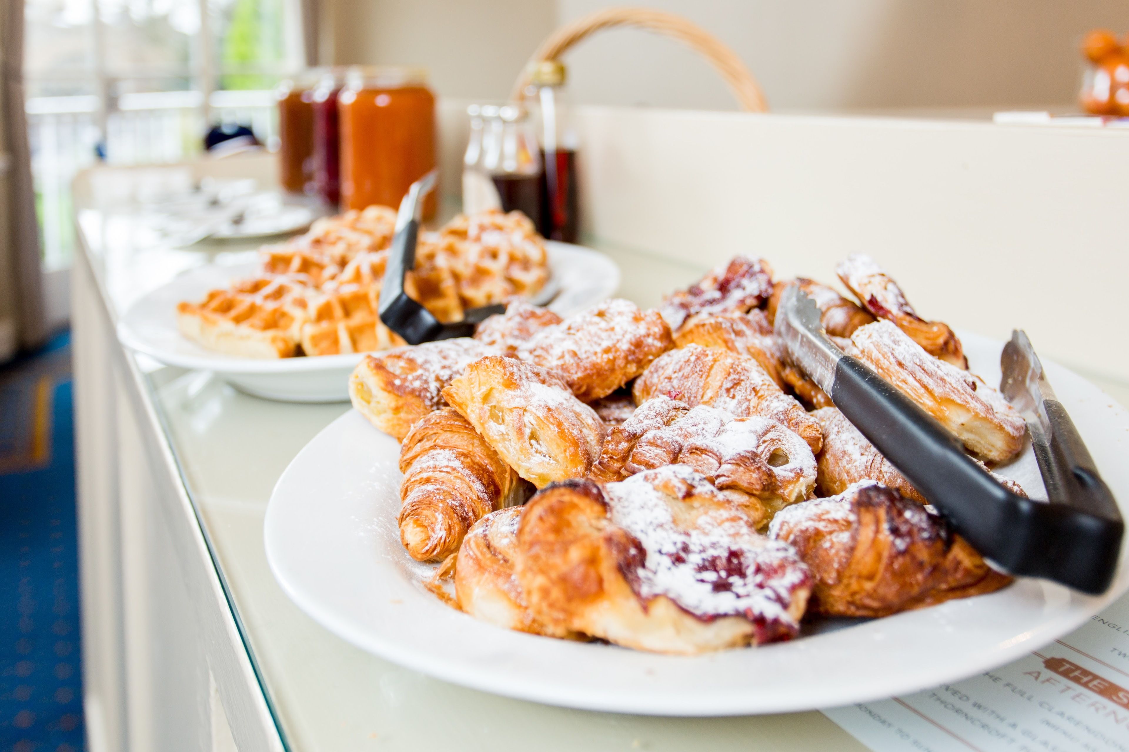 Taula de buffet amb plats de pastissos i una cafetera.
