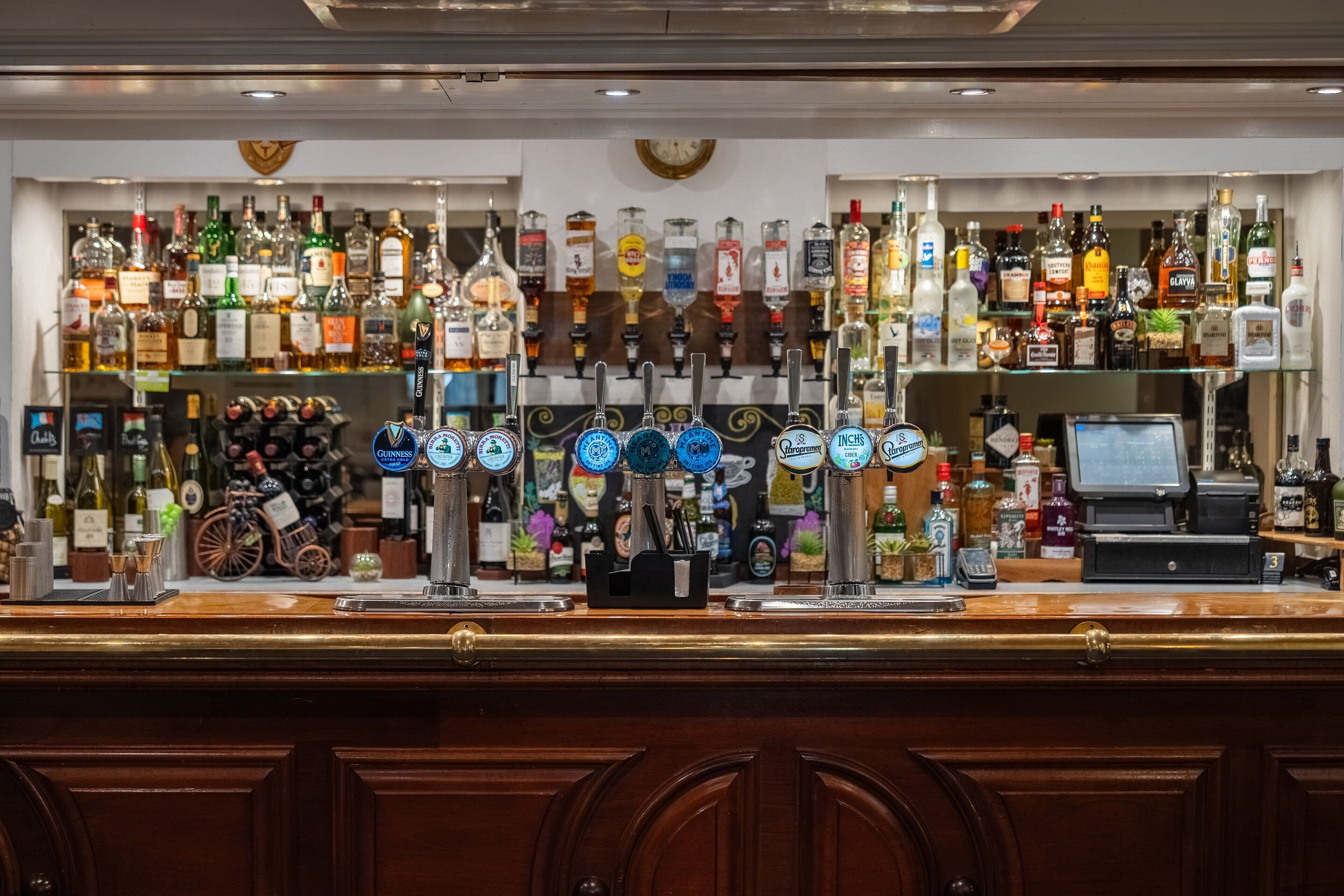 A bar area with multiple liquor dispensers and a variety of bottles.