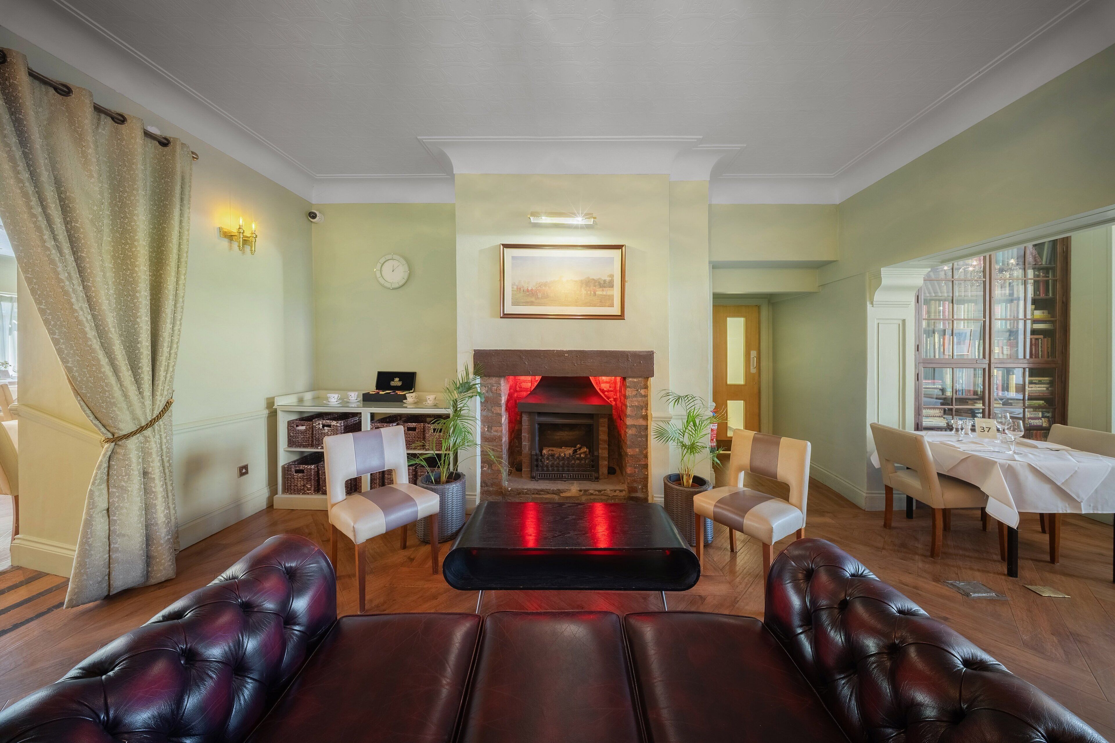 A living room with a fireplace, leather sofas, a dining table, and a bookshelf.