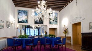 Un comedor formal con una gran araña, manteles azules y sillas de madera.